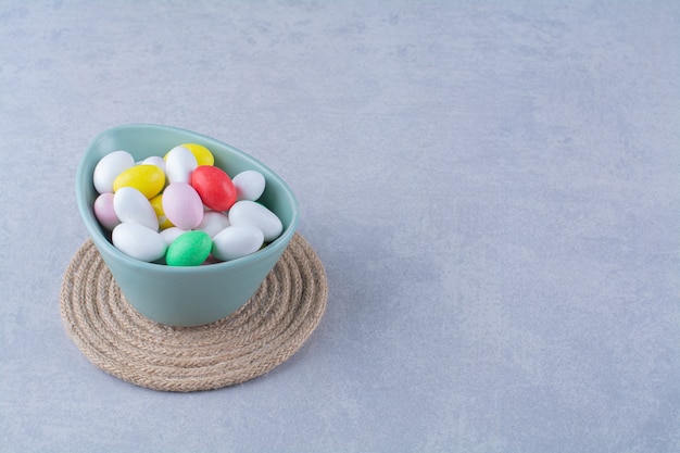 Un Bol Bleu Profond Rempli De Bonbons Aux Haricots Colorés Sur Une Table Grise.