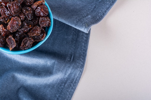 Bol bleu de prunes biologiques séchées placé sur fond blanc. photo de haute qualité