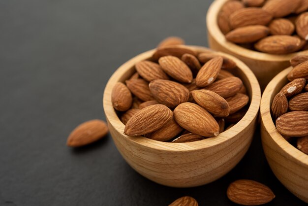 Bol en bois aux amandes sur fond noir. Vue de dessus.