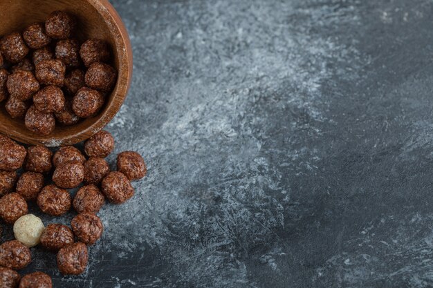 Un bol en bois avec des boules de maïs sucré sur fond gris.