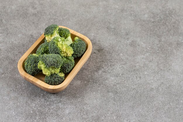 Bol en bois de brocoli frais et sain sur table en pierre.