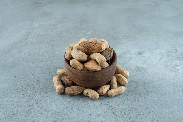 Bol en bois de cacahuètes croustillantes placé sur fond de pierre