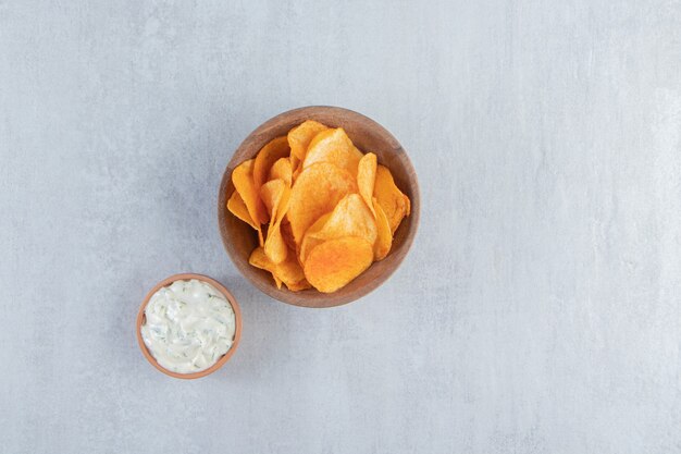 Bol en bois de chips épicées et sauce sur pierre.