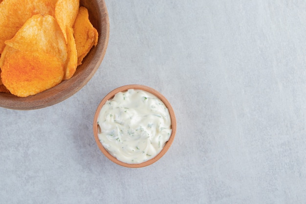 Photo gratuite bol en bois de chips épicées et sauce sur pierre.