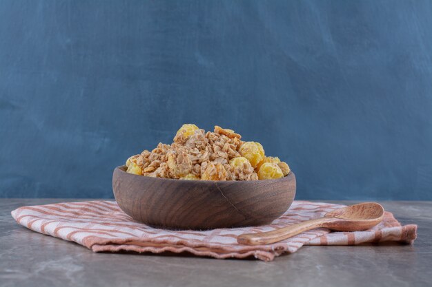 Un bol en bois avec des cornflakes sains et une cuillère en bois vide.