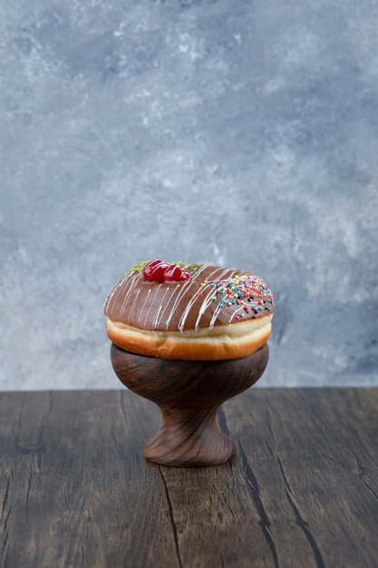 Bol en bois de délicieux beignet avec glaçage au chocolat et arrose sur table en bois.