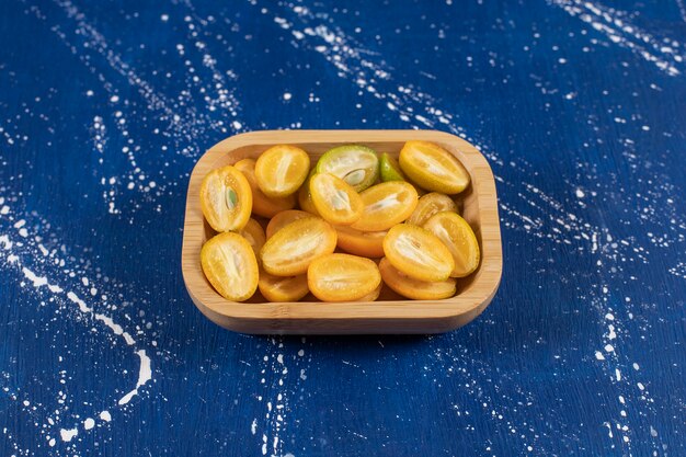 Bol en bois de fruits frais tranchés de kumquat sur une surface en marbre