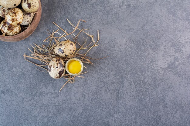 Bol en bois d'oeufs de caille crus sur table en pierre.