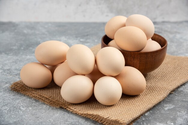 Bol en bois d'oeufs crus biologiques sur une surface en marbre.