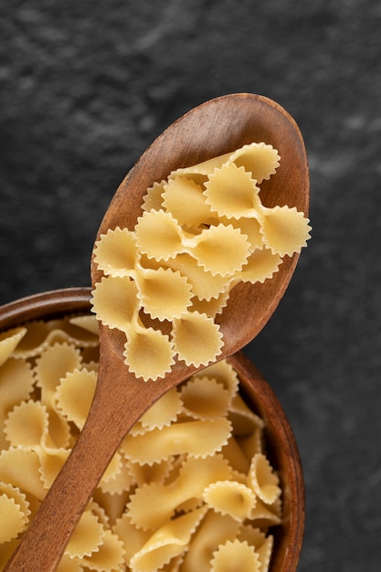 Photo gratuite un bol en bois rempli de macaroni farfalle tonde cru.