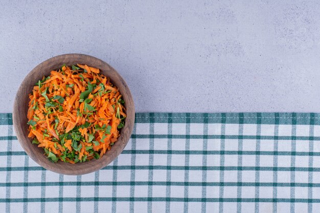 Bol en bois de salade de carottes sur une nappe sur fond de marbre. photo de haute qualité