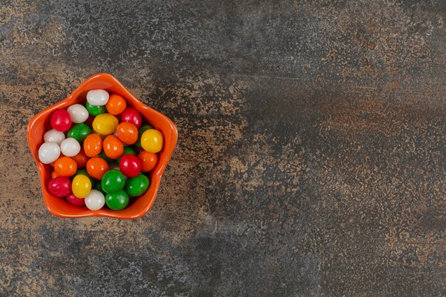 Bol de bonbons colorés sur marbre.