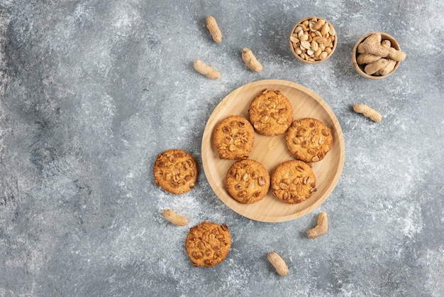 Bol de cacahuètes et biscuits aux cacahuètes biologiques sur table en marbre.