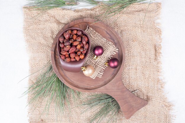 Bol de canneberges séchées et boules de Noël sur planche de bois. Photo de haute qualité