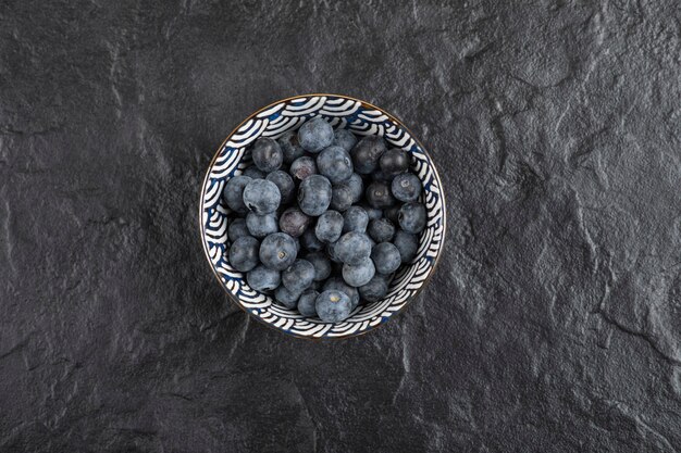 Bol en céramique de délicieux bleuets frais sur une surface noire
