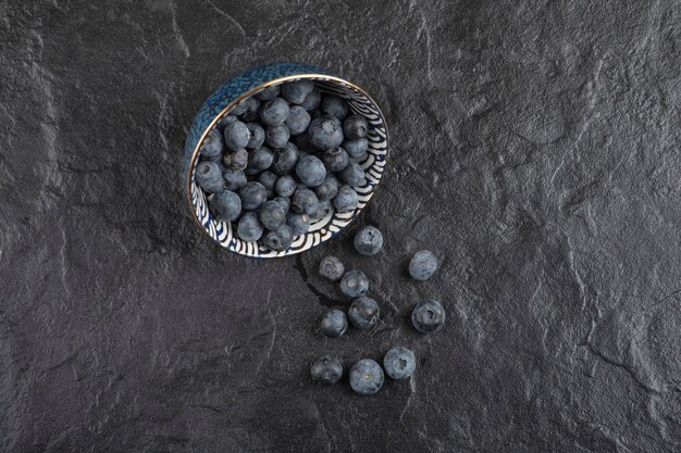 Bol en céramique de délicieux bleuets frais sur une surface noire