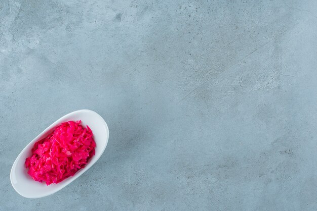 Un bol de choucroute fermentée rouge, sur la table bleue.