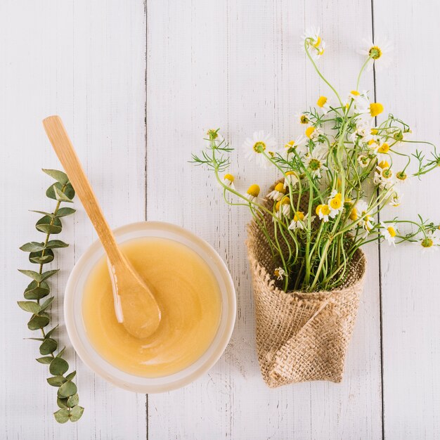 Bol de citron et de belles fleurs de camomille sur fond en bois