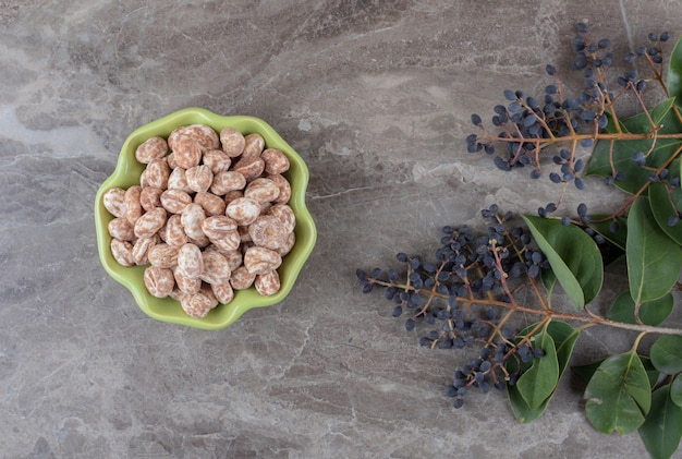 Un bol de confiserie avec du raisin et des feuilles, sur la surface en marbre