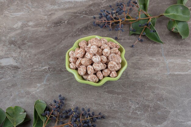 Un bol de confiserie avec du raisin et des feuilles sur la surface en marbre