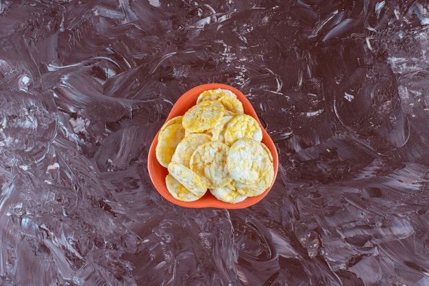 Photo gratuite un bol de délicieuses chips au fromage , sur la table en marbre.