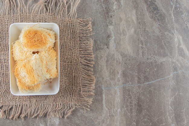 Un bol de dessert turc kadayif sur une texture sur bleu.