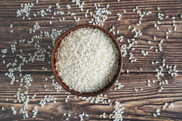 Bol avec du riz sur le bureau avec des grains dispersés