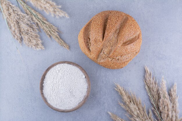 Bol de farine de pain et de tiges d'herbe de plumes séchées sur la surface en marbre