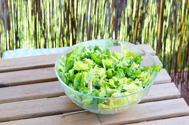 Bol de feuilles de salade verte fraîche sur une table en bois