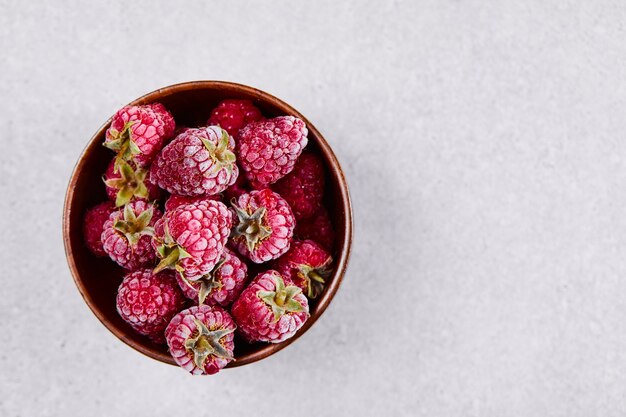 Bol de framboises rouges fraîches sur fond blanc.