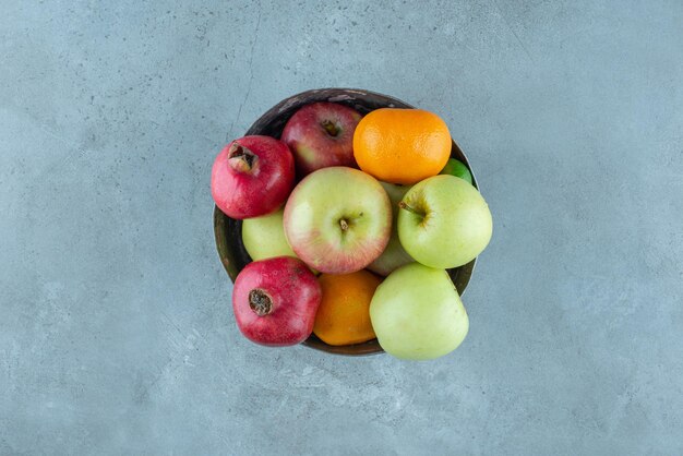 Bol de fruits avec grenades, pommes et mandarines.