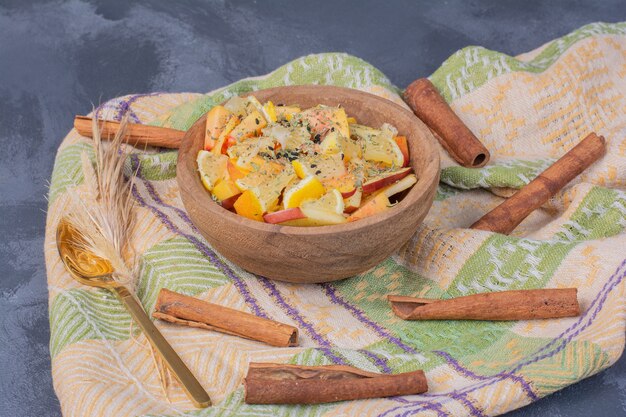 Bol De Fruits En Tranches Avec De La Cannelle Et Un Chiffon Sur Bleu.