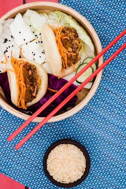 Bol de grains de riz avec gua bao et salade dans le paquebot en bambou sur napperon