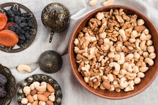 Bol gravé rond avec noix; fruits morts et bol mélangé de noix sur la nappe