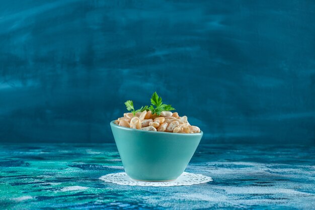 Un bol de haricots blancs au persil , sur la table bleue.