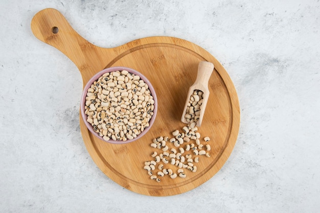 Bol de haricots blancs avec cuillère sur une planche à découper.