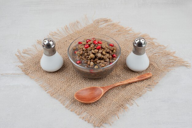 Bol de haricots bouillis avec des graines de grenade et du sel sur la toile de jute.