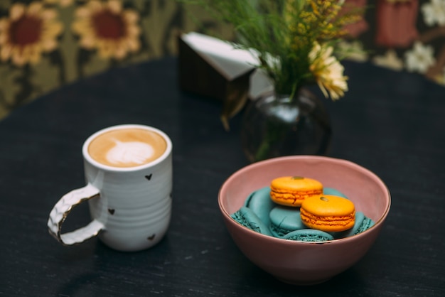 Photo gratuite bol avec des macarons près de café