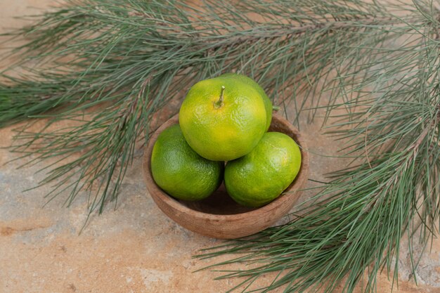 Bol de mandarines fraîches sur table en marbre avec branche.