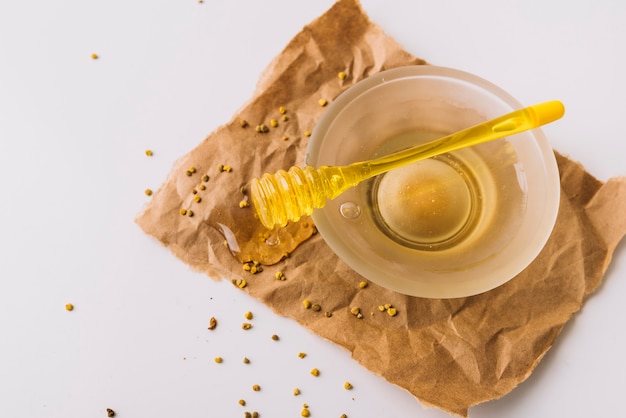 Photo gratuite bol de miel; graines de noyer et de pollen d'abeille sur papier brun