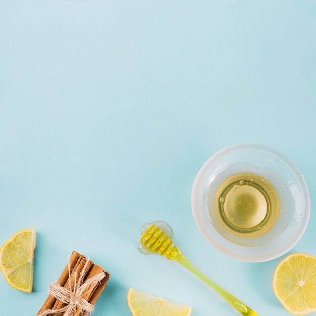 Bol de miel près de louche; citron et cannelle sur fond bleu