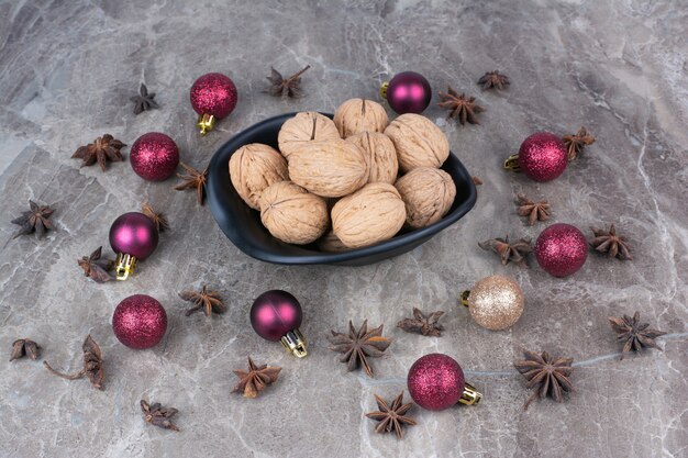 Bol de noix avec clous de girofle et boules de Noël.