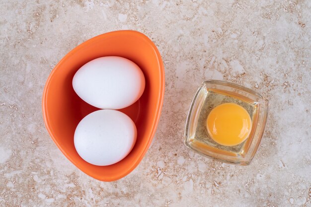 Photo gratuite un bol orange avec des œufs de poule blancs frais