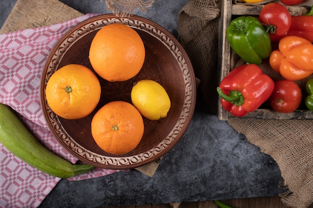 Un Bol D'oranges Avec Un Plateau De Poivrons.