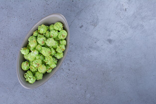 Bol ovale rempli de bonbons de maïs soufflé sur une surface en marbre