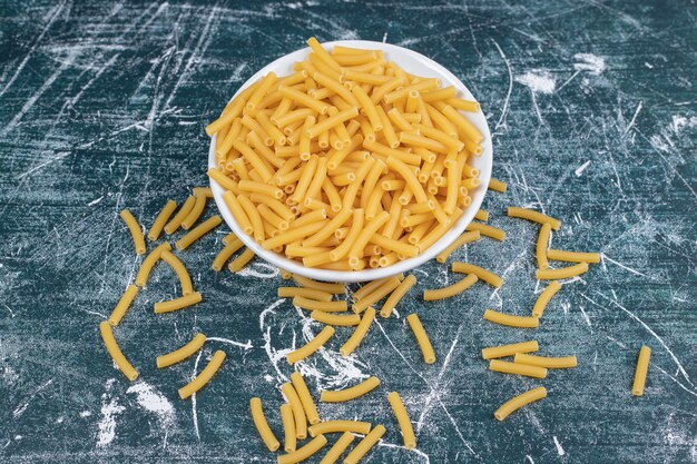 Bol de pâtes penne sur fond bleu. Photo de haute qualité