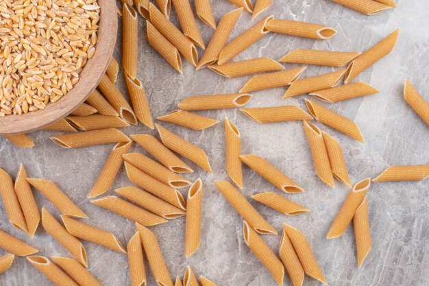 Un bol de pâtes penne saupoudrées de céréales dans un bol, sur le marbre.