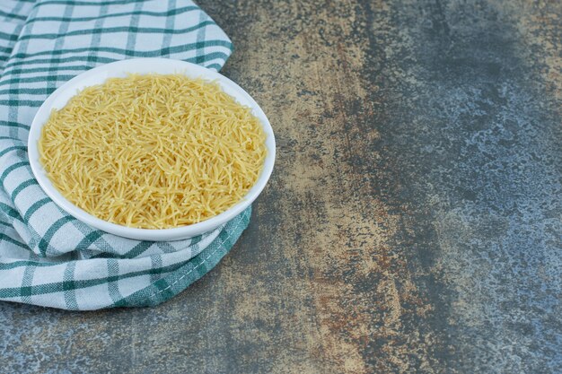 Un bol de pâtes sur la serviette, sur la surface en marbre.