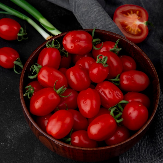 Bol plein de tomates sur une surface noire