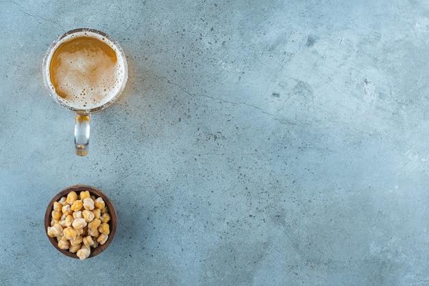 Photo gratuite un bol de pois chiches et un verre de bière sur du marbre.